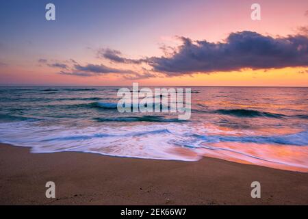 sea beach with dramatic sky at sunrise. beautiful vacation background. waves rolling on the sand in morning light Stock Photo
