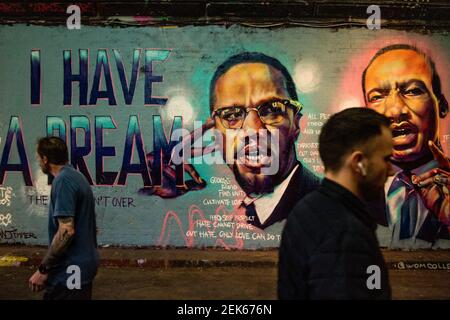 London, UK. 17th June, 2020. A man walks past a mural of Malcom X and  Martin Luther King paying tribute to George Floyd, a Black man who died in  police custody in