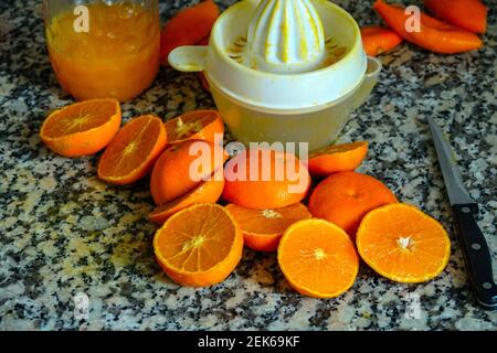 Fresh oranges ready for squeezing to make orange juice on granite kitchen work surface. Stock Photo