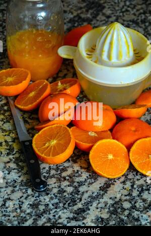 Fresh oranges ready for squeezing to make orange juice on granite kitchen work surface. Stock Photo