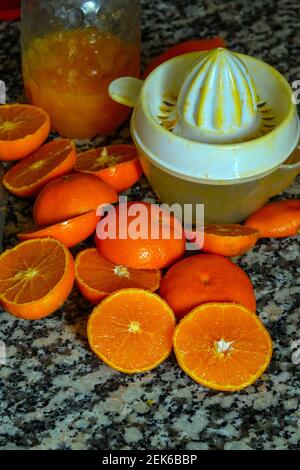 Fresh oranges ready for squeezing to make orange juice on granite kitchen work surface. Stock Photo