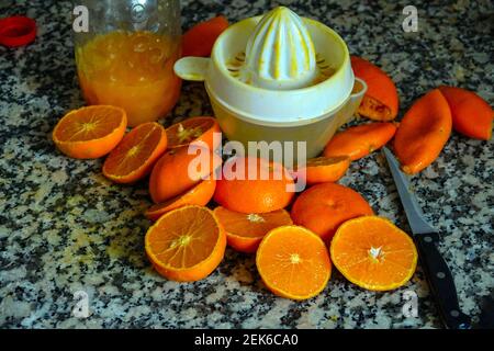 Fresh oranges ready for squeezing to make orange juice on granite kitchen work surface. Stock Photo