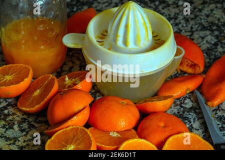 Fresh oranges ready for squeezing to make orange juice on granite kitchen work surface. Stock Photo
