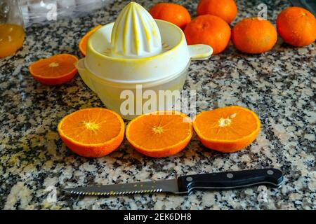 Fresh oranges ready for squeezing to make orange juice on granite kitchen work surface. Stock Photo
