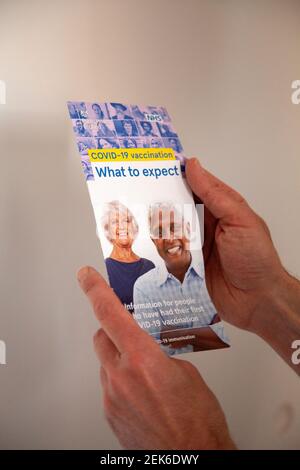Man Holding Covid Vaccination 'What to Expect' Leaflet Stock Photo