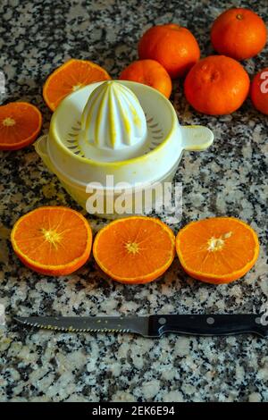 Fresh oranges ready for squeezing to make orange juice on granite kitchen work surface. Stock Photo