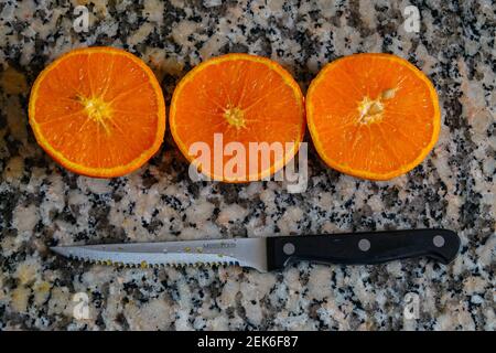 Fresh oranges ready for squeezing to make orange juice on granite kitchen work surface. Stock Photo