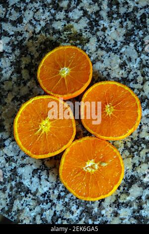 Fresh oranges ready for squeezing to make orange juice on granite kitchen work surface. Stock Photo
