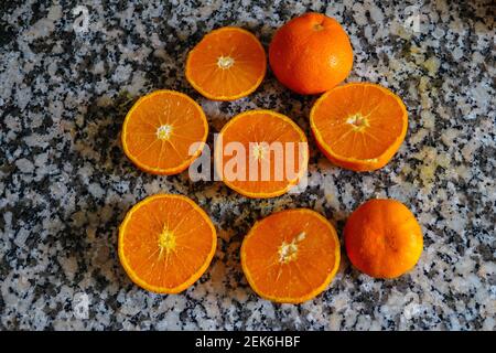 Fresh oranges ready for squeezing to make orange juice on granite kitchen work surface. Stock Photo