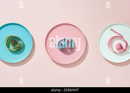 three plate with measuring tape on color background. Diet concept Stock Photo