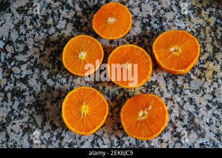Fresh oranges ready for squeezing to make orange juice on granite kitchen work surface. Stock Photo