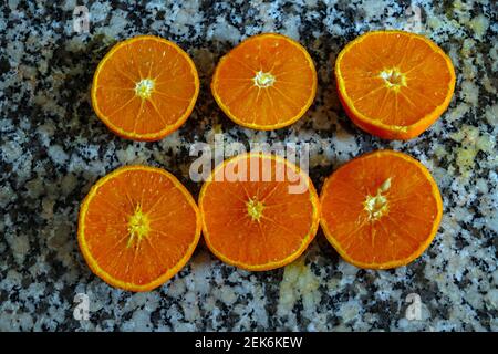 Fresh oranges ready for squeezing to make orange juice on granite kitchen work surface. Stock Photo