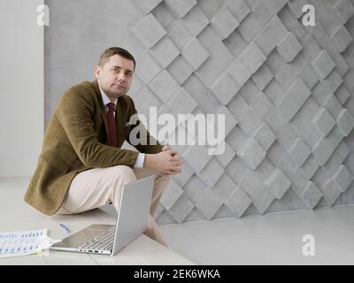 Portrait of a businessman looking into the camera. Laptop and paper. Empty space. Stock Photo