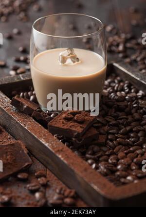 https://l450v.alamy.com/450v/2ek73ay/glass-with-ice-cubes-of-irish-cream-baileys-liqueur-in-wooden-tray-with-coffee-beans-and-powder-with-dark-chocolate-on-dark-wood-background-top-view-2ek73ay.jpg