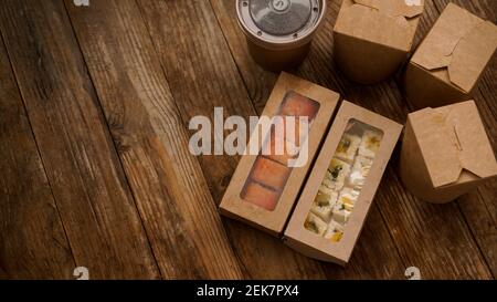 Asian food delivery. Packaging for sushi and woks. Food in paper containers on wooden background Stock Photo