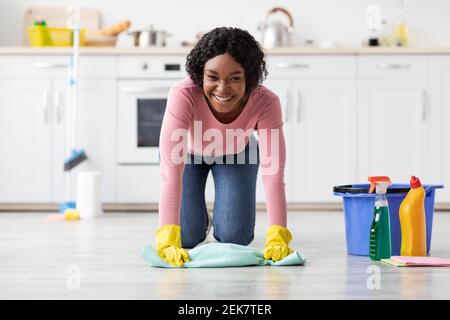 Happy african american woman cleaning floor in kitchen Stock Photo