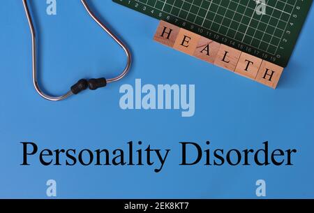 Layout of Stethoscope, graph pad and wooden block with the text PERSONALITY DISORDER on blue background Stock Photo