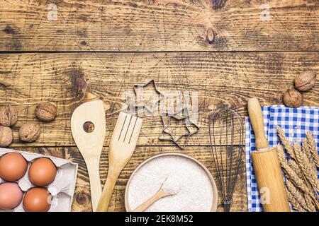 Frame of baking and cooking pastry or cake with ingredients and utensils. Eggs, nuts, flour and wheat on rustic wooden background with copy space for Stock Photo