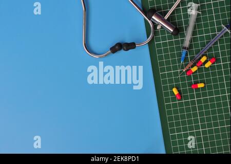 Layout of Stethoscope, graph pad, reflex hammer, syringes and pills with blank space for text on blue background Stock Photo