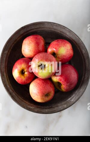 Fresh red apples in rustic plate on white marble background. Top view. Stock Photo