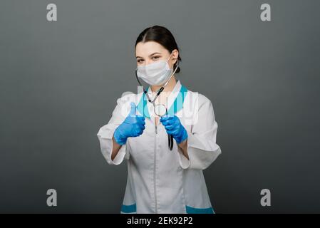 Beautiful female doctor in protective mask looking away and thinking about something. Stock Photo