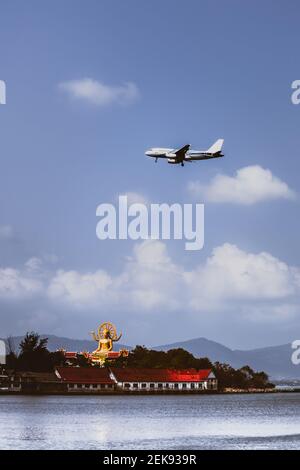 Passenger airplane flying over above big buddha in koh samui island. Stock Photo