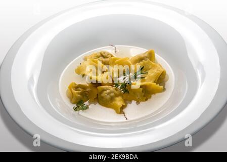 ravioli del plin in broth, typical Piedmontese stuffed pasta from the Langhe, Italy, in white plate Stock Photo