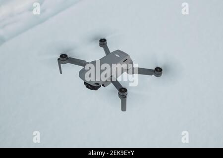 Kharkiv, Ukraine - February 21, 2021: Dji Mavic Mini 2 drone flying close-up. New quadcopter gadget on white snow winter background looking left Stock Photo