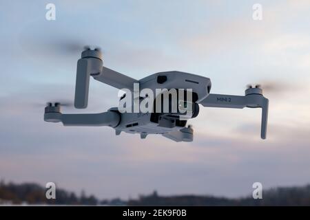 Kharkiv, Ukraine - February 21, 2021: Dji Mavic Mini 2 drone flying in sky with clouds. New quadcopter device hovering on pastel sunset sky background Stock Photo
