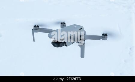Kharkiv, Ukraine - February 21, 2021: Dji Mavic Mini 2 drone flying close-up. New quadcopter gadget on white snow winter background. Looking left Stock Photo