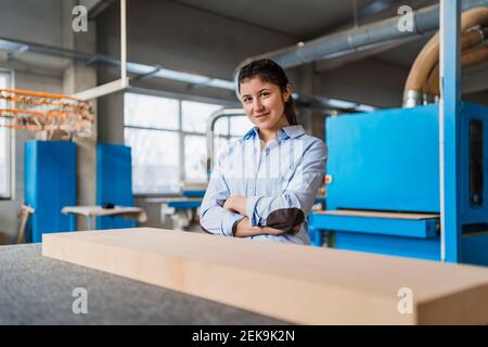 Smiling businesswoman with arms crossed standing at industry Stock Photo