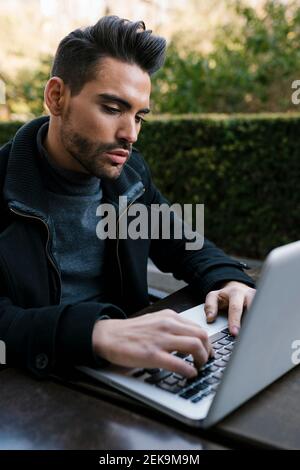 Handsome man using laptop while sitting at table Stock Photo