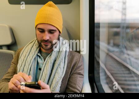 Man using mobile phone while sitting in train Stock Photo
