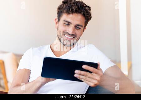 Mid adult man using digital tablet while sitting at home Stock Photo