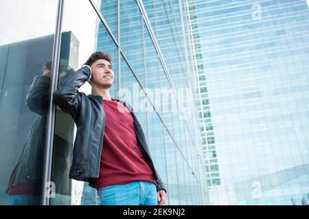 Smiling man using virtual reality simulator against glass building Stock Photo