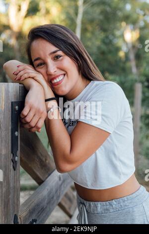 Close-up of beautiful woman leaning on wooden fence in forest Stock Photo