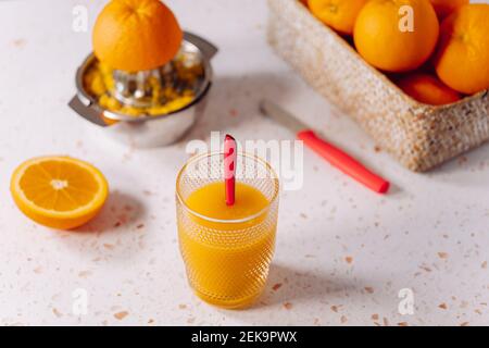 Glass of orange juice with spoon and stainless steel juicer on modern marble Stock Photo