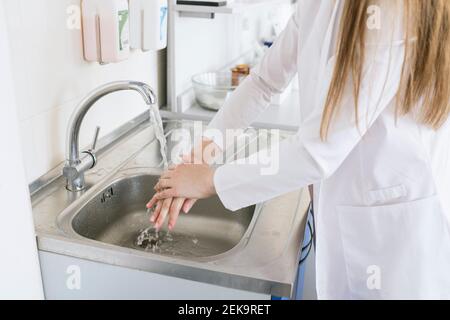 Crop view of female scientist washing hands at laboratory Stock Photo