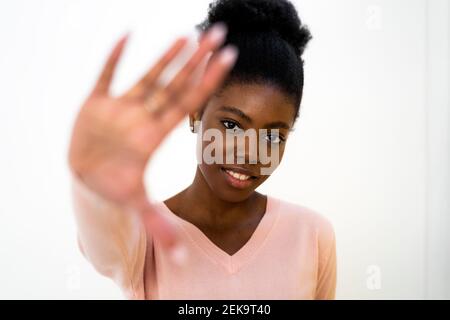 Woman showing stop gesture while standing against white background Stock Photo
