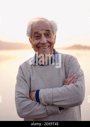 Cheerful senior man standing with arms crossed against sky Stock Photo