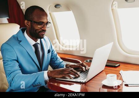 Young businessman working on laptop in airplane Stock Photo