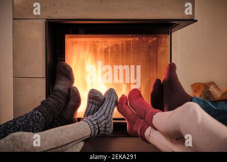 Family warming up feet in woolen socks by fireplace in living room