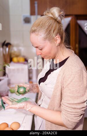 Woman painting eggs while standing at home for Easter Tradition Stock Photo