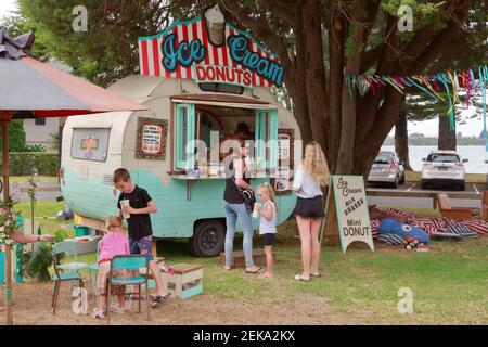 An ice cream and donut stall operating out of a tiny vintage caravan at a traveling fair Stock Photo