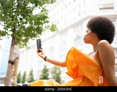 Young woman taking selfie through smart phone in city Stock Photo