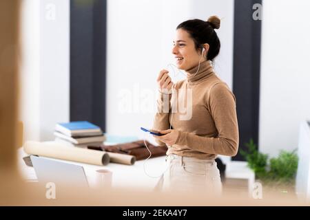 Young woman having phone call while talking through earphones Stock Photo