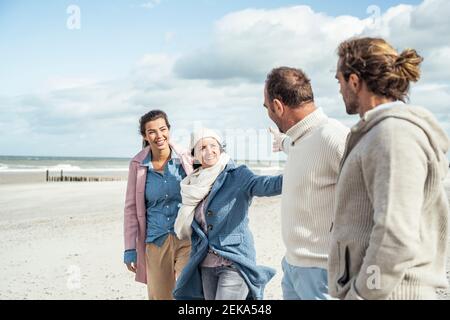 Group of adult friends greeting on coastal beach Stock Photo