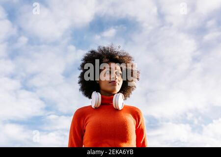 Contemplating Afro woman looking away against cloudy sky Stock Photo