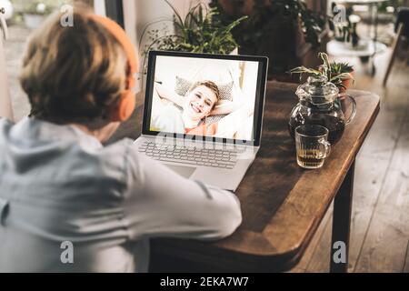 Mother having video call with smiling daughter through video call on table at home Stock Photo
