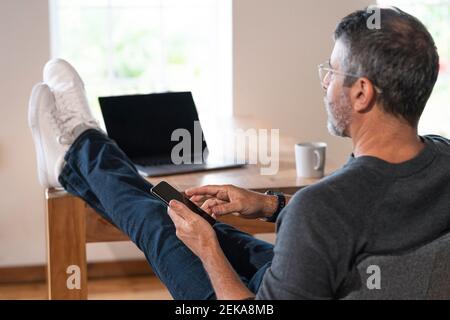 Businessman using mobile phone while sitting at home office Stock Photo